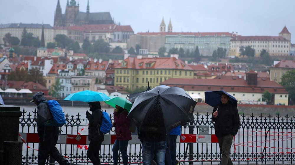 Ludźo wuchodźuja so w dešćiku při Wołtawskej w Praze. / Foto: Dana Kesnerova/XinHua/dpa