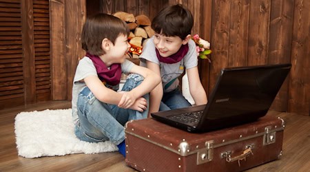 Zwei lächelnde Jungen vor einem Notebook