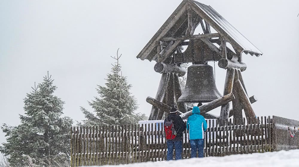 Zwei Wanderer stehen vor der Friedensglocke auf dem Fichtelberg. (Archivbild) / Foto: Kristin Schmidt/dpa-Zentralbild/dpa