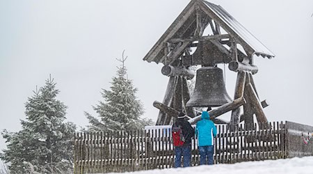 Zwei Wanderer stehen vor der Friedensglocke auf dem Fichtelberg. (Archivbild) / Foto: Kristin Schmidt/dpa-Zentralbild/dpa