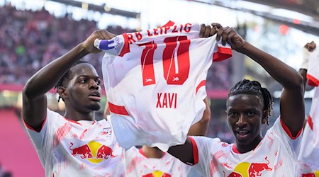 Leipzig's Castello Lukeba (l) and Amadou Haidara hold up a jersey of the injured Xavi Simons after the 2:1. / Photo: Hendrik Schmidt/dpa