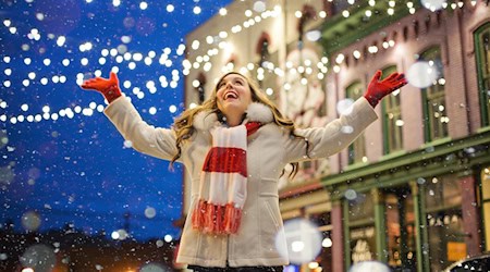 Glücklich lächelnde Frau auf einer weihnachtlich erleuchteten Einkaufsstraße