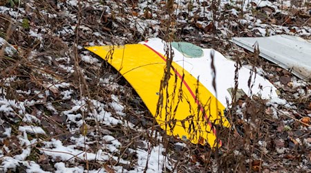 Auf einem Trümmerteil des abgestürzten Flugzeugs sind die DHL-Farben zu sehen. / Foto: Mindaugas Kulbis/AP