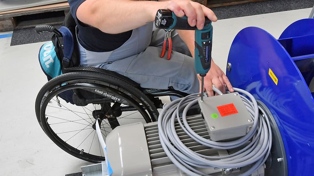 Ein Mann im Rollstuhl bei Montagearbeiten an einem Arbeitsplatz für Motorklemmen (Archivbild) / Foto: Hendrik Schmidt/zb/dpa