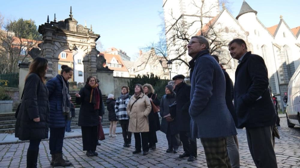 Die Mitglieder der KAS im Gespräch auf dem Plätzchen vor dem Bahrmannschen Brauhaus mit Architektin Stephanie Vogel (in blau vorne links) und Stadtarchitektin Katja Lamnek (mit buntem Schal) (im Hintergrund das Tuchmachertor). Foto: Stadt Meißen