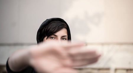Jugendlicher verdeckt sein Gesicht mit der Hand