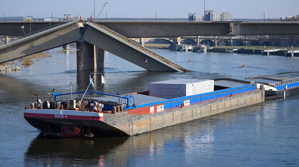 Ein Frachter fährt als erstes Schiff unter der teilweise eingestürzten Carolabrücke hindurch. / Foto: Robert Michael/dpa