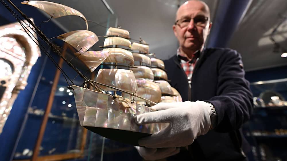 Kostbarkeiten aus Perlmutt: Steffen Dietz, Leiter des Erlebnismuseums Perlmutter, zeigt ein etwa 100 Jahre altes Modellschiff.  / Foto: Elisa Schu/dpa