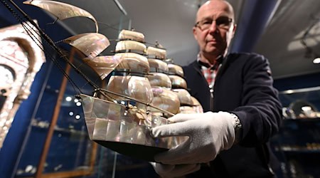 Kostbarkeiten aus Perlmutt: Steffen Dietz, Leiter des Erlebnismuseums Perlmutter, zeigt ein etwa 100 Jahre altes Modellschiff.  / Foto: Elisa Schu/dpa