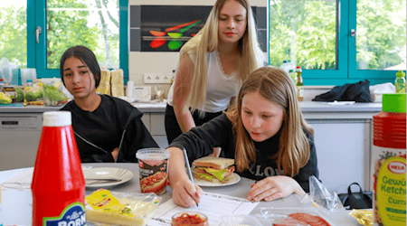 Eine Studentin unterstützt Schülerinnen in der Schulküche der Richard-von-Schlieben-Oberschule in Zittau bei der Projektarbeit zum Thema Ernährung. 