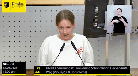 Eine junge Frau spricht am Podium in ein Mikrofon