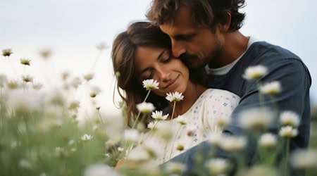 Paar sitzt vertraut auf blühender Margeritenwiese