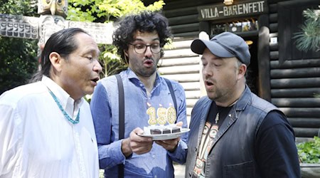 Kevn Manygoats, Björn Reinemer und Robin Leipold gratulieren im Karl-May-Museum mit Minitorte zum 150. Winnetou-Geburtstag. Foto: Stadt Radebeul 