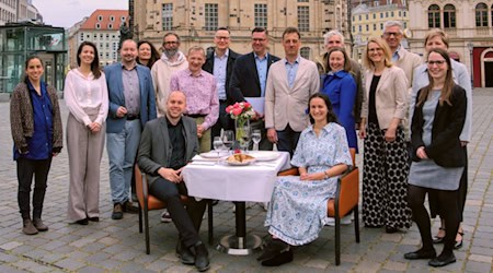 Gruppenfoto: Das Palais Sommer-Team und Partner. Ein festlich gedeckter Tisch steht symbolisch für das Festival und die Möglichkeit, Tische mit Getränken und Speisen online zu reservieren. 