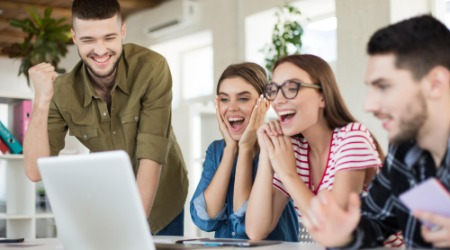 Junges Team freut sich am Laptop über Erfolge im Online-Marketing.