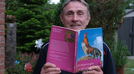 Jurik Müller mit einem seiner veröffentlichten Bücher der Bauernregeln.  / Foto: Sebastian Willnow/dpa