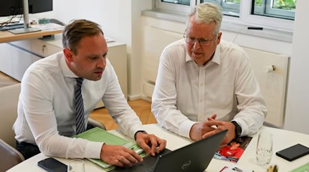 Der Sächsische Ausländerbeauftragte Geert Mackenroth präsentiert dem Landtagspräsidenten einen Jahresbericht am Laptop. Foto: Landtag