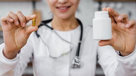 Ärztin hält eine Kapsel und eine Dose Nahrungsergänzungsmittel in den Händen