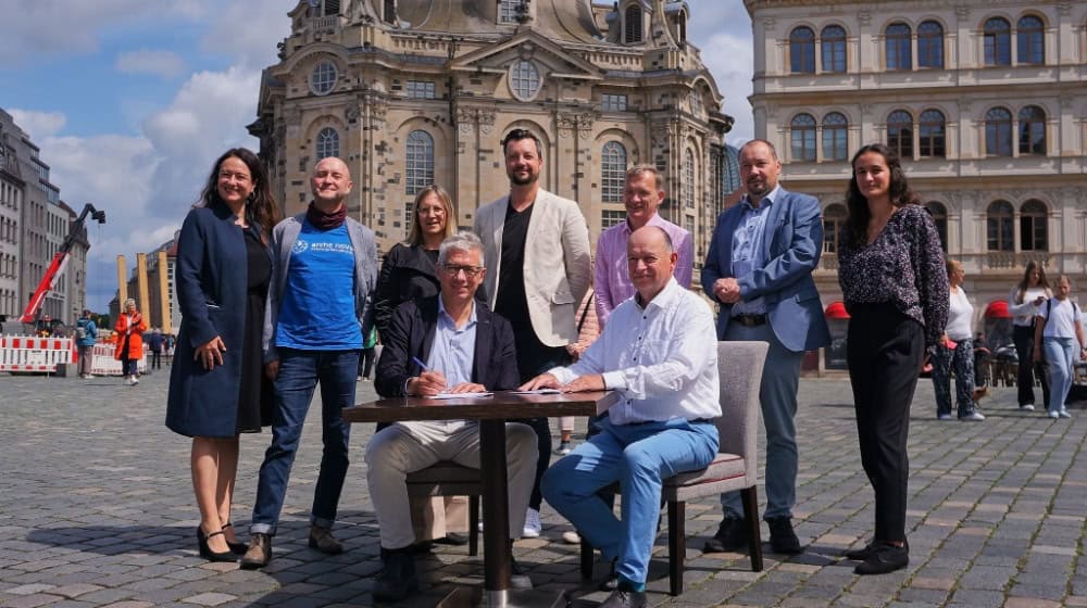 Gruppenfoto Palais Sommer und Partner; im Vordergrund Unterzeichnung Vereinbarung Strategische Bildungspartnerschaft von Jörg Polenz, Geschäftsführer Palais Sommer, und Dr. Jens Ola, Geschäftsführer arche noVa e.V. 
