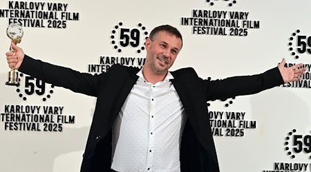 Der slowakische Regisseur Miro Remo posiert mit seiner Auszeichnung in der Hand. Miro gewann den Hauptpreis des 59. Karlsbader Filmfestivals. / Foto: Slavomír Kubeš/CTK/dpa
