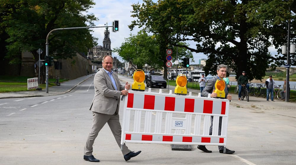 Dirk Hilbert (FDP, l), Lord Mayor of the City of Dresden, and Stephan Kühn (Alliance 90/The Greens), Mayor of the City of Dresden, carry the last barrier fence away from the Terrassenufer. / Photo: Robert Michael/dpa
