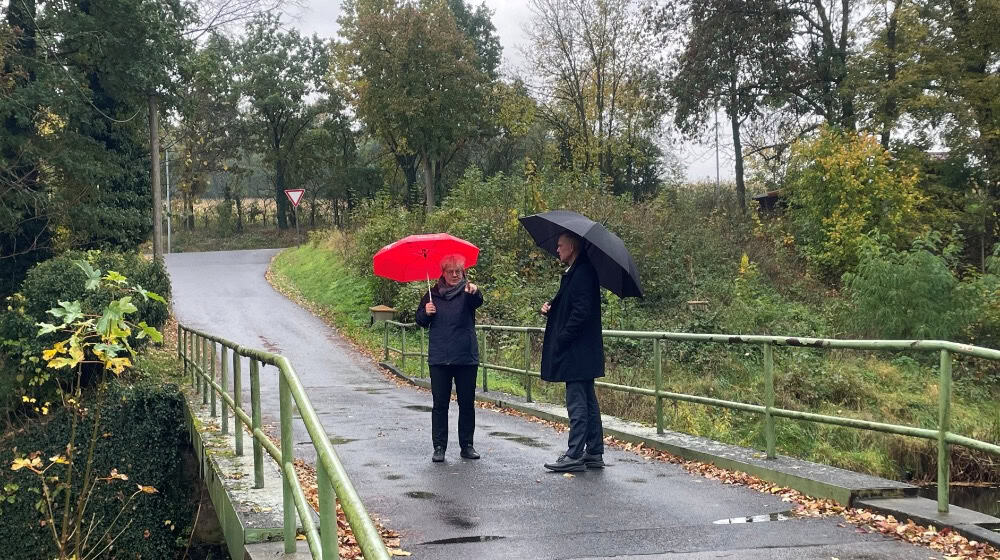 Stehen im Regen: Bürgermeisterin Michaela Ritter und Landrat Ralf Hänsel auf der Brücke über die Große Röder in Großdittmannsdorf Bildquelle: Landratsamt Meißen