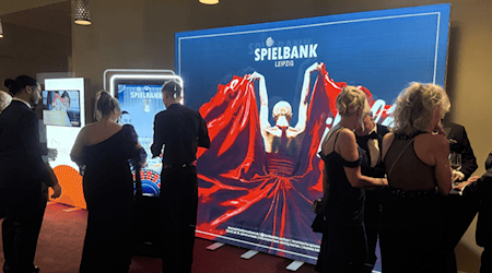 Besucher in Abendgarderobe vor dem „¡Olé!“-Leuchtmotiv der Spielbank Leipzig beim Opernball 2025.