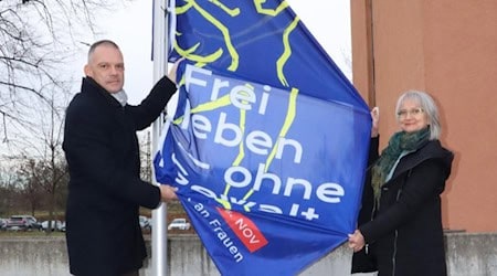 Landrat Ralf Hänsel und die Gleichstellungsbeauftragte Gabriele Fänder hissen die Aktionsfahne vor dem Landratsamt in Meißen. Foto: Landratsamt Meißen