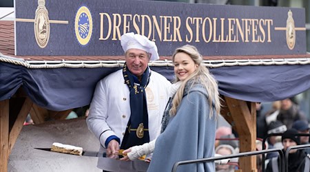 Майстер-пекар Райнер Ізраель та дівчина-штоллен Йоганна Ворм представляють шматок гігантського штоллена на Дрезденському фестивалі штолленів. / Фото: Sebastian Kahnert/dpa