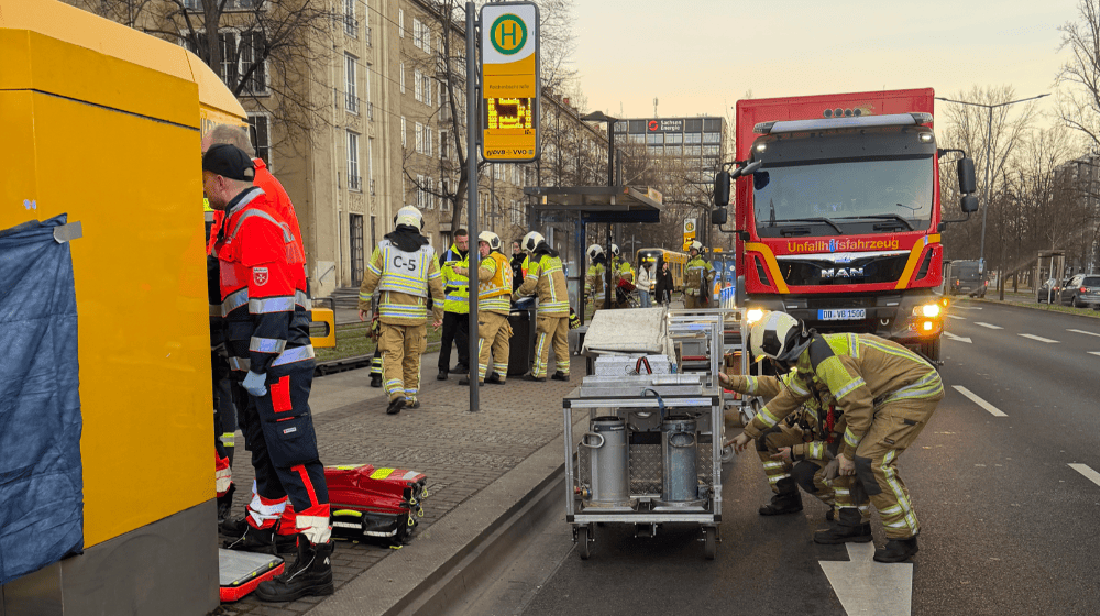 Auf dem Foto nur schwer zu erkennen: die unfallbeteiligte Straßenbahn (links, von Fahrkartenautomat und Rettungskräften verdeckt). Foto: Feuerwehr Dresden