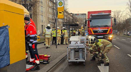 Auf dem Foto nur schwer zu erkennen: die unfallbeteiligte Straßenbahn (links, von Fahrkartenautomat und Rettungskräften verdeckt). Foto: Feuerwehr Dresden