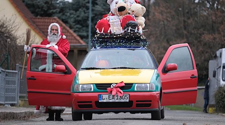 André Adelinia ist als Leipziger Weihnachtsmann mit einem reich dekorierten Auto unterwegs. / Foto: Sebastian Willnow/dpa