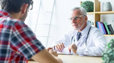 Ein älterer Arzt im weißen Kittel und mit Stethoskop führt ein Beratungsgespräch mit einem Patienten in einer Praxis – symbolisch für vertrauensvolle Arzt-Patienten-Kommunikation und individuelle medizinische Betreuung.