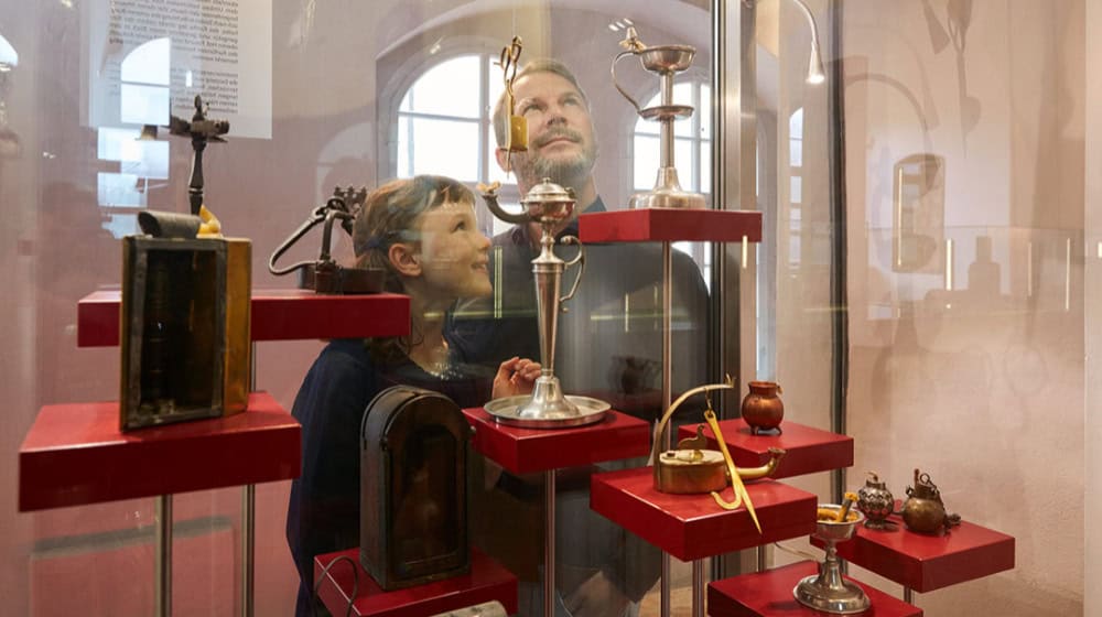 Vater und Tochter an der Vitrine mit Kerzenscheren im Museum Schloss Klippenstein. Foto: Juliane Mostertz