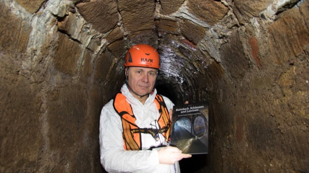 Experte Frank Männig zeigt im ältesten Kanal Dresdens hinter der Schinkelwache sein Buch über die Dresdner Entwässerungsgeschichte. Das stellt er bei einer Lesung am 27. Januar, 16 Uhr, im Klärwerk Kaditz vor. Foto: Peter Hilbert