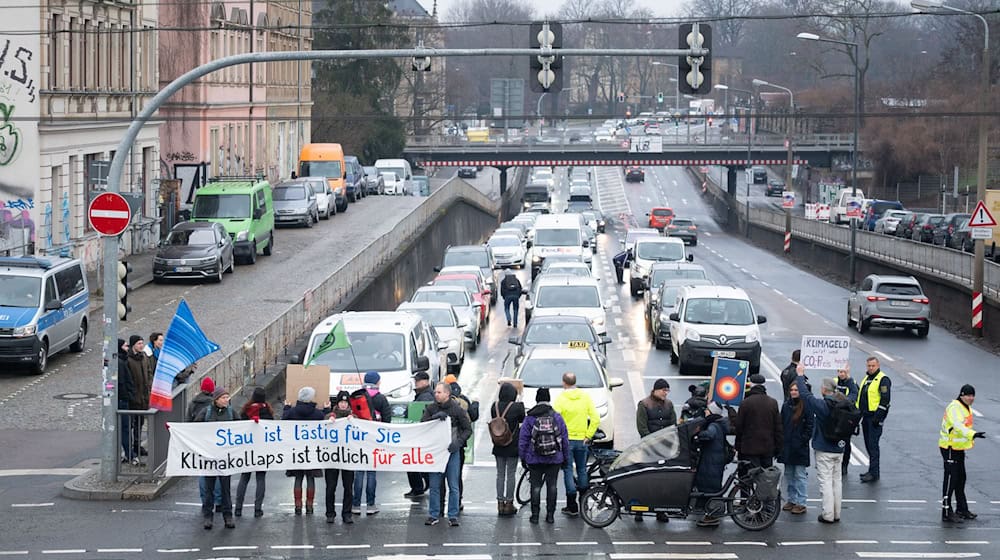 Klima-Aktivsten haben bei einer Straßenblockade eine «Wärmewende» in Dresden hin zu erneuerbaren Wärmequellen verlangt.  / Foto: Sebastian Kahnert/dpa