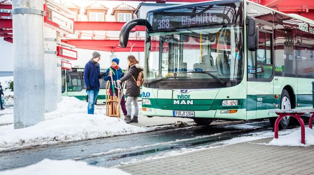 A modern VVO bus navigating a scenic route through Saxony's countryside near Meissen, with passengers boarding at a rural stop.