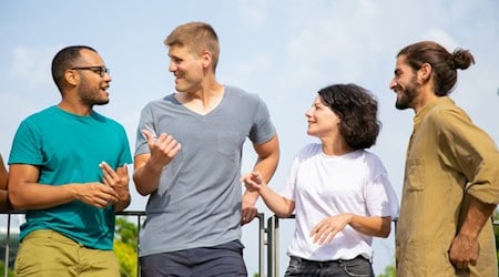 Vier junge Erwachsene stehen draußen zusammen und unterhalten sich entspannt während einer Pause