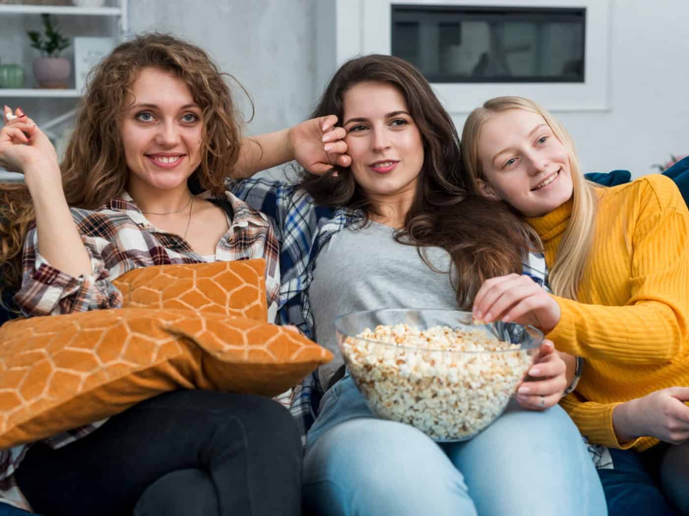 Drei Freundinnen schauen gemeinsam nostalgische Filme mit Popcorn