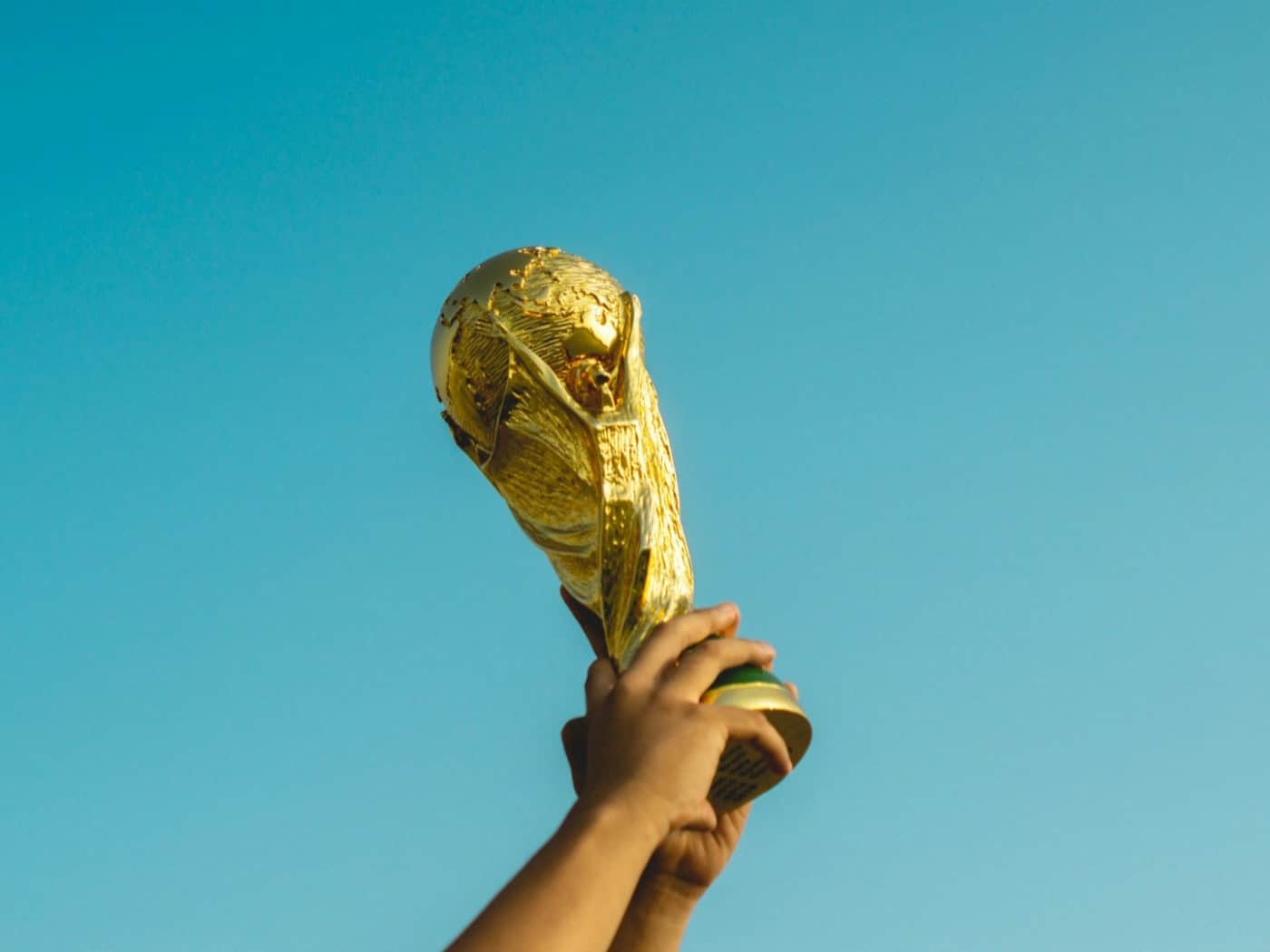 Goldener WM-Pokal wird triumphierend in den Himmel gehalten – Symbol für den anstehenden WM-Härtetest zwischen der Schweiz und Deutschland.
