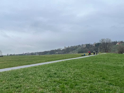 Radfahrer auf dem Elberadweg in Dresden-Blasewitz, Blickrichtung Waldschlößchenbrücke und Elbschlösser bei bewölktem Wetter.