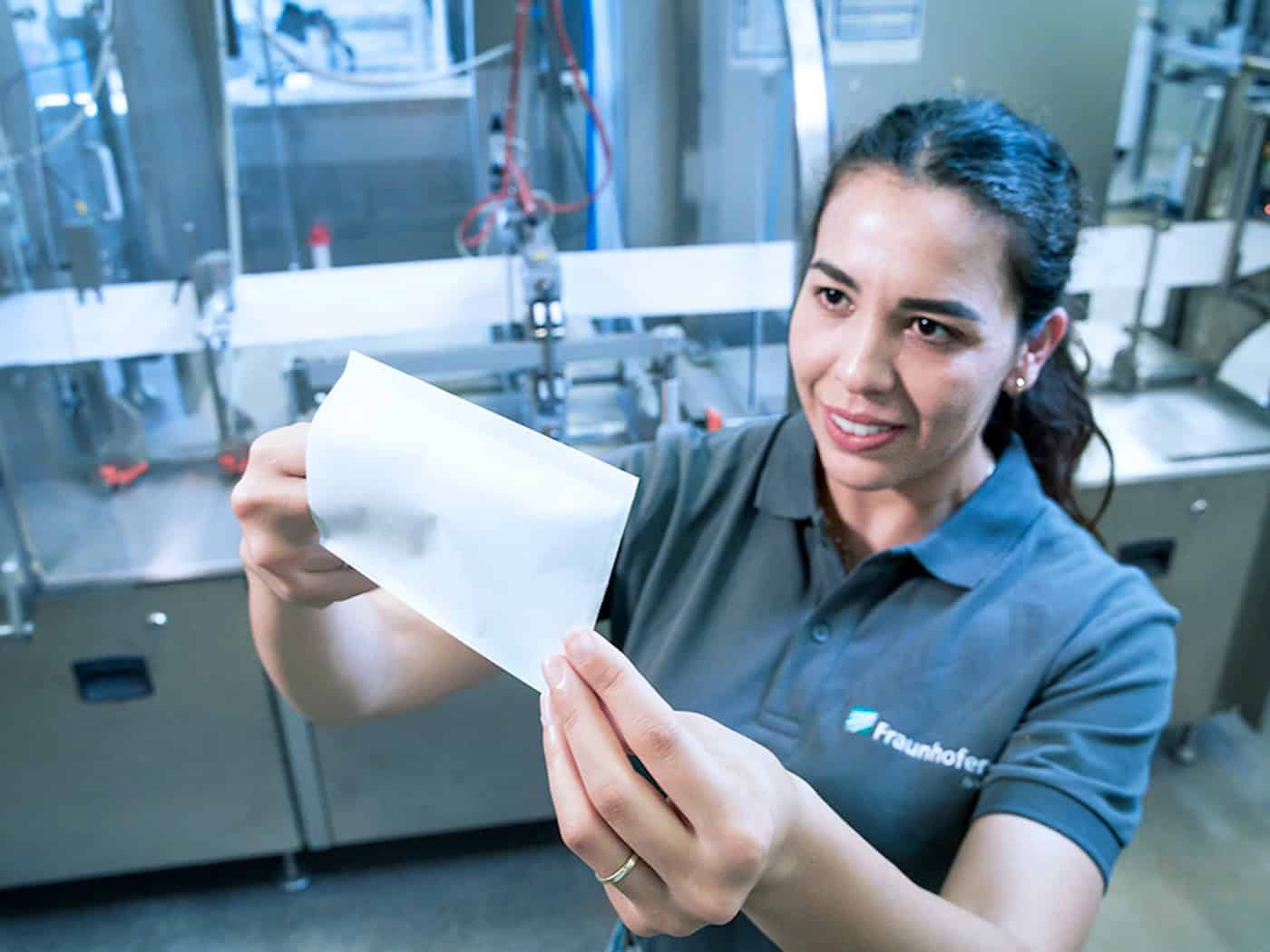 So sieht die Verpackung der Zukunft aus: Eine Mitarbeiterin des Fraunhofer IVV begutachtet eine Papiertüte, die per Laser und Heißsiegelverfahren verschlossen wurde.