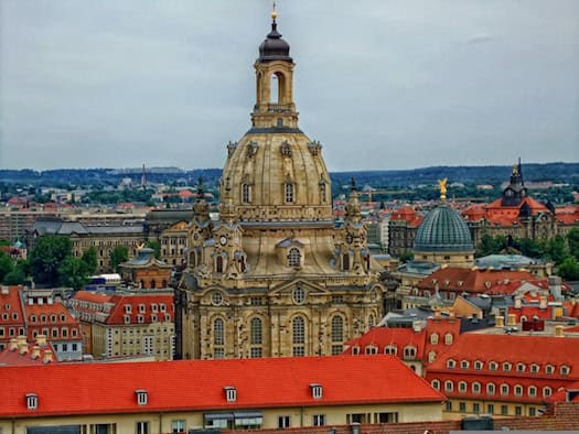 Panorama der Dresdner Altstadt mit der markanten Kuppel der Frauenkirche und umliegenden Wohn- und Geschäftshäusern mit roten Ziegeldächern.