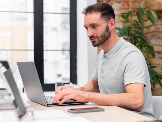 Ein Mann arbeitet konzentriert an einem Laptop in einem modernen Büro