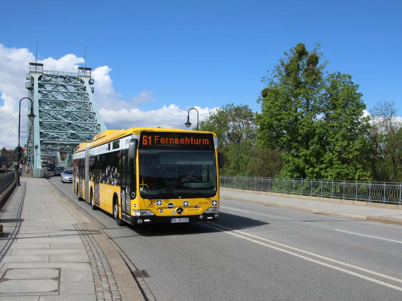 Gelber DVB-Linienbus der Linie 61 auf der Brücke Blaues Wunder in Dresden bei blauem Himmel.