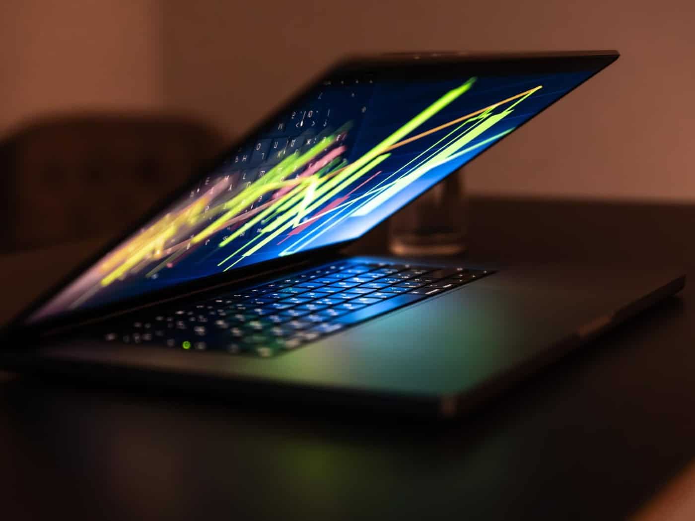 Offener Laptop mit dynamischem, farbigem Datenstrom auf dem Bildschirm.