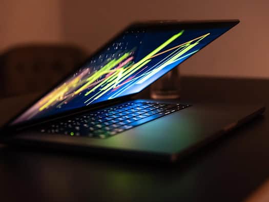 Offener Laptop mit dynamischem, farbigem Datenstrom auf dem Bildschirm.