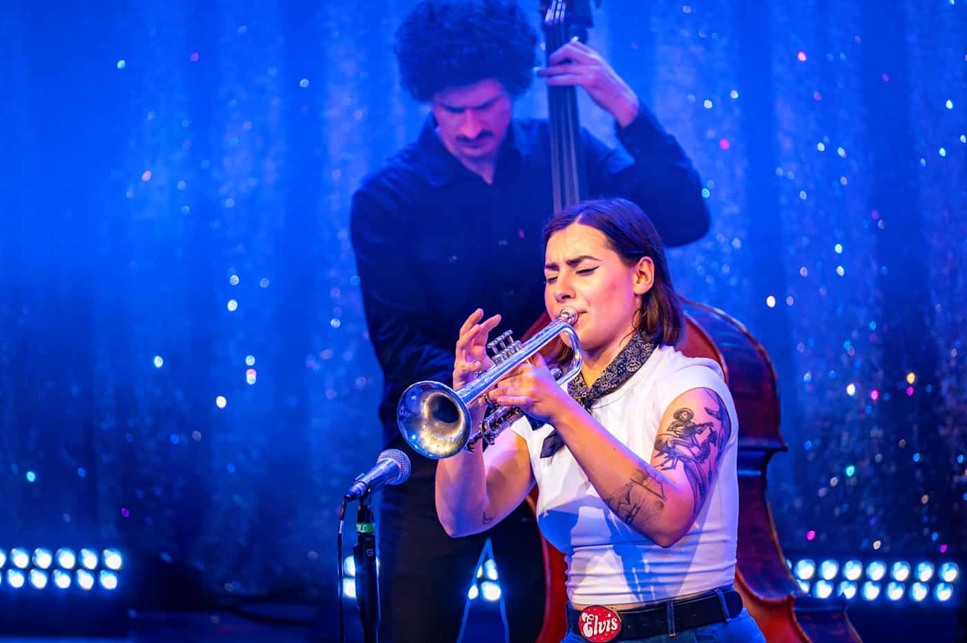 Die Musikerin Angela Strandberg spielt Trompete auf einer blau beleuchteten Bühne während des Dixieland Festivals Dresden; im Hintergrund ist ein Kontrabassist zu sehen.