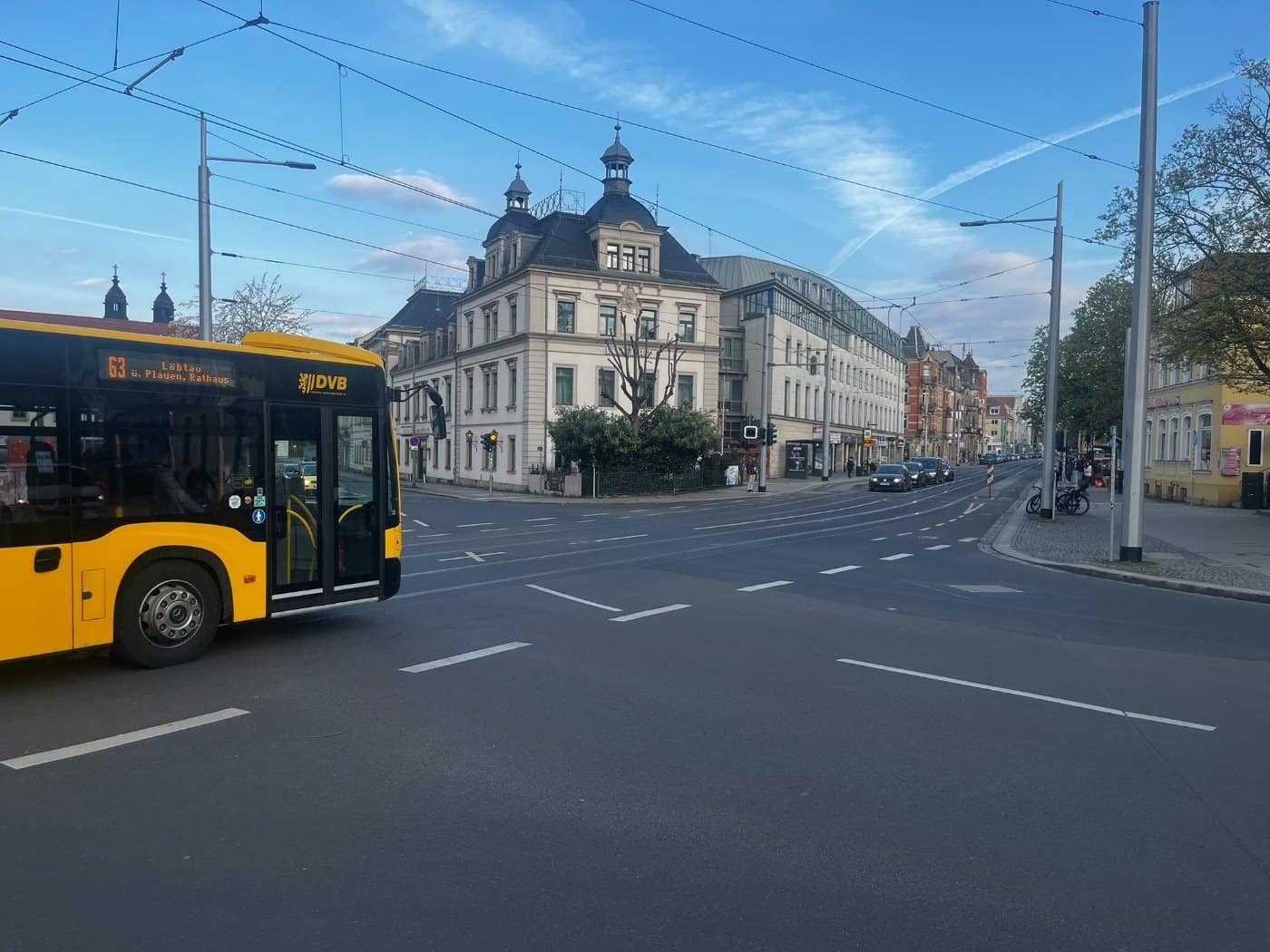 Ein gelber Bus der Dresdner Verkehrsbetriebe (DVB) passiert den Wasaplatz. Im Hintergrund sind historische Gebäude der Caspar-David-Friedrich-Straße und Oberleitungen der Straßenbahn zu sehen.