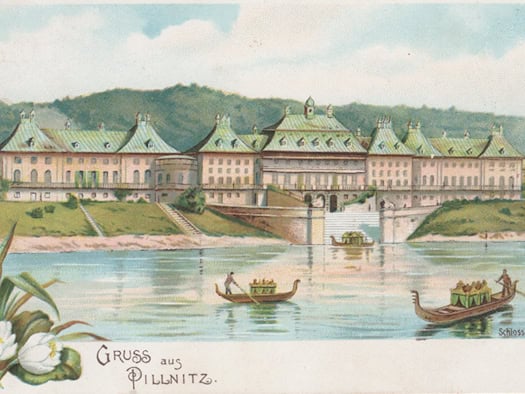 Historische farbige Postkarte von Schloss Pillnitz bei Dresden aus der Zeit um 1900. Zu sehen ist das Wasserpalais vom Elbufer aus, davor fahren mehrere prunkvolle Gondeln mit Passagieren auf dem Fluss. Links im Vordergrund sind Blumen illustriert, unten steht der Schriftzug „Gruss aus Pillnitz“.